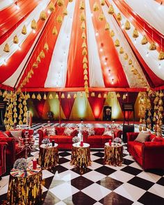 a large red and white tent with gold decorations on it's ceiling, set up for a party