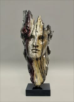 a sculpture of a man's head with hair and eyes on a black base