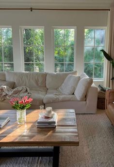 a living room with couches, coffee table and large windows in the back ground