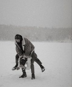 two people are playing in the snow on their skateboards and one person is holding another