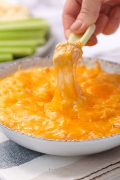 a person is dipping cheese into a casserole dish