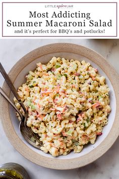 a bowl filled with macaroni salad next to a jar of pickles