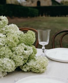 the table is set with white plates and silverware, which are also decorated with green hydrangeas