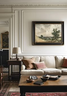 a living room filled with furniture and a painting on the wall above it's coffee table