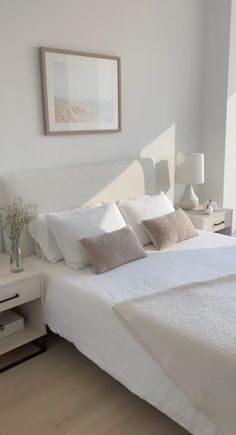 a white bed sitting in a bedroom next to a painting on the side of a wall