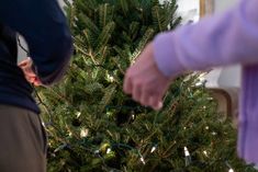 two people standing in front of a christmas tree