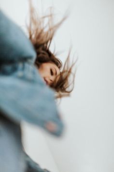 a woman is flying through the air with her hair blowing in the wind and looking up