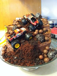 a cake with chocolate frosting and monster trucks on top