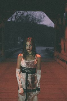 a woman standing in the dark with her hands on her hips and wearing white gloves