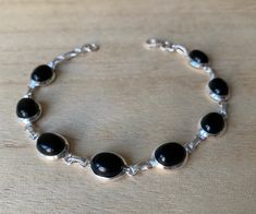 Lovely black onyx and sterling silver bracelet. The bracelet has 8 individual black onyx in an oval shape.  The bracelet measure 19 cm long and it is almost 0.8 cm wide. The bracelet can be  easily  adjusted from 19 cm to 17 cm.  The high quality of our stones is what it makes this bracelet so precious.  A perfect present for her on any occasion St Valentine Day, Birthday, Anniversary, Travelling or Christmas. Black onyx is a powerful protection stone as well as to hep absorbs and transforms neg Modern Black Oval Link Jewelry, Black Sterling Silver Jewelry With Oval Link, Modern Black Sterling Silver Bracelet, Formal Black Sterling Silver Round Bracelet, Formal Black Round Sterling Silver Bracelet, Modern Black Sterling Silver Bracelet For Formal Occasions, Elegant Black Sterling Silver Bracelet With Polished Finish, Polished Black Bracelets, Classic Black Sterling Silver Bracelet