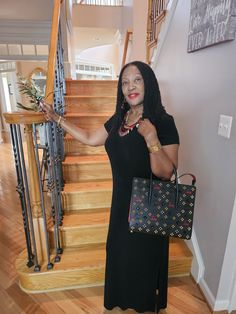 a woman is standing in front of the stairs with her handbag and purse on her hip