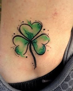 a woman's stomach with a four leaf clover tattoo on her back side ribcage