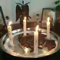 a cake with lit candles sitting on top of a metal plate in front of a mirror