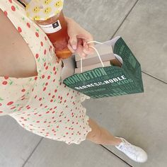 a woman holding a paper bag with donuts in it's hand and an apple on top