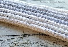 a crocheted blanket laying on top of a wooden floor next to a piece of wood