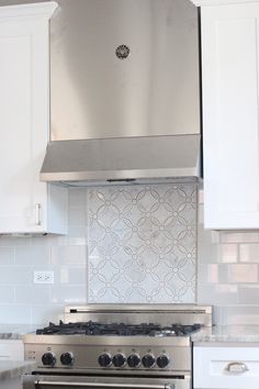 a stove top oven sitting inside of a kitchen next to white cabinets and counter tops