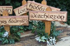 four wooden signs with writing on them sitting on a table in front of some flowers