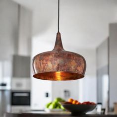 a light hanging over a kitchen counter next to a bowl filled with fruit on top of a wooden table