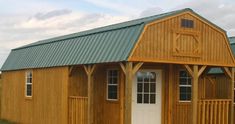 a small wooden building with green roof and white door