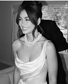 black and white photograph of a woman in a dress with pearls on her neck, smiling at the camera