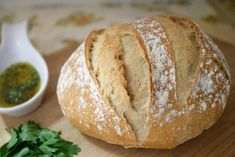 a loaf of bread sitting on top of a wooden cutting board next to a bowl