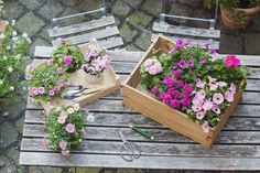 two wooden boxes filled with flowers sitting on top of a table next to each other