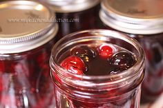 jars filled with cherries sitting on top of a table