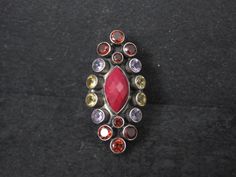 This gorgeous ring is a product of Nicky Butler. It features a 7x13mm faceted ruby accented by garnets, citrines and amethysts. The face of this ring measures 1 1/2 inches north to south. Size: 6 Marks: NB, 925, India Condition: Excellent Unique Multi-stone Ruby Ring, Gorgeous Ring, Ruby Ring, Rings Statement, Citrine, Statement Rings, Garnet, The Face, Ruby