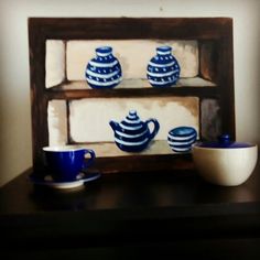 a painting of blue and white pottery on a shelf next to a cup, saucer and bowl