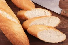 several loaves of bread next to a knife on a cutting board