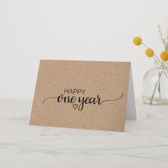 a card with the words happy one year written on it next to a vase filled with flowers