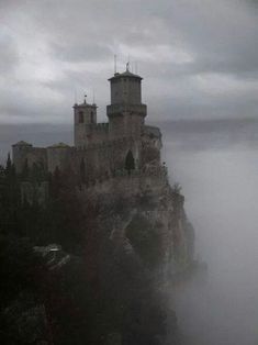 a castle on top of a cliff in the fog