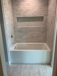 a bath tub sitting inside of a bathroom next to a doorway with a light on