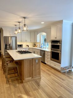 a large kitchen with an island in the middle and stainless steel appliances on both sides