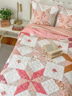 a quilted bed with a book on top of it next to a nightstand and lamp