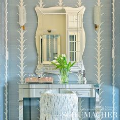 a mirror sitting on top of a table next to a white vanity with a vase filled with flowers