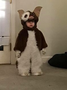 a little boy dressed up as a racoon standing in the middle of a room