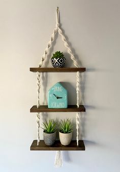 two wooden shelves with plants on them and a sign hanging from the wall behind them