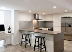 a modern kitchen with stainless steel appliances and bar stools next to the countertop