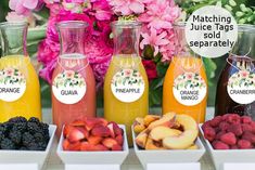 there are many different types of juices in the trays on the table with flowers behind them