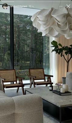 a living room filled with furniture and a large window covered in curtains next to a forest