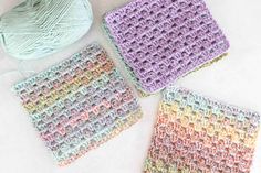 three crocheted squares sitting next to each other on a white surface with yarn