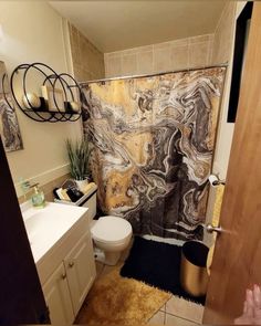 a bathroom with a toilet, sink and shower curtain in it's center area