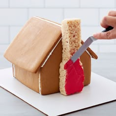 someone cutting into a gingerbread house with a knife