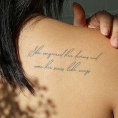 the back of a woman's shoulder with writing on her left arm and hand