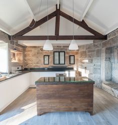 an open kitchen with stone walls and wooden beams