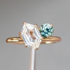 two different colored stones are on top of a gold ring with white and blue diamonds