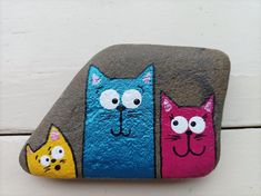 three cats painted on rocks with eyes and noses