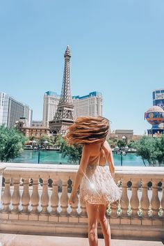 a woman standing in front of the eiffel tower with her hair blowing in the wind