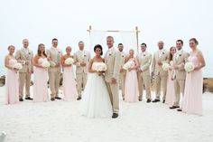 a bride and groom with their wedding party on the beach